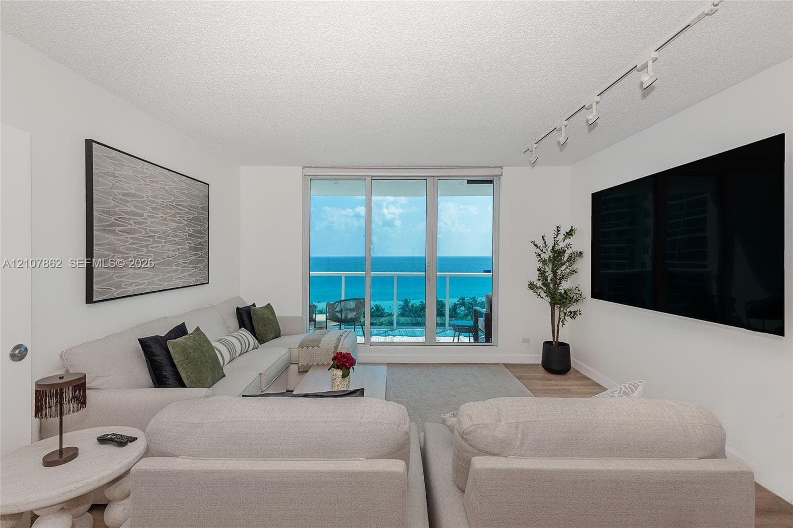 Living area featuring floor-to-ceiling glass sliding doors, wood-finish flooring, and track lighting