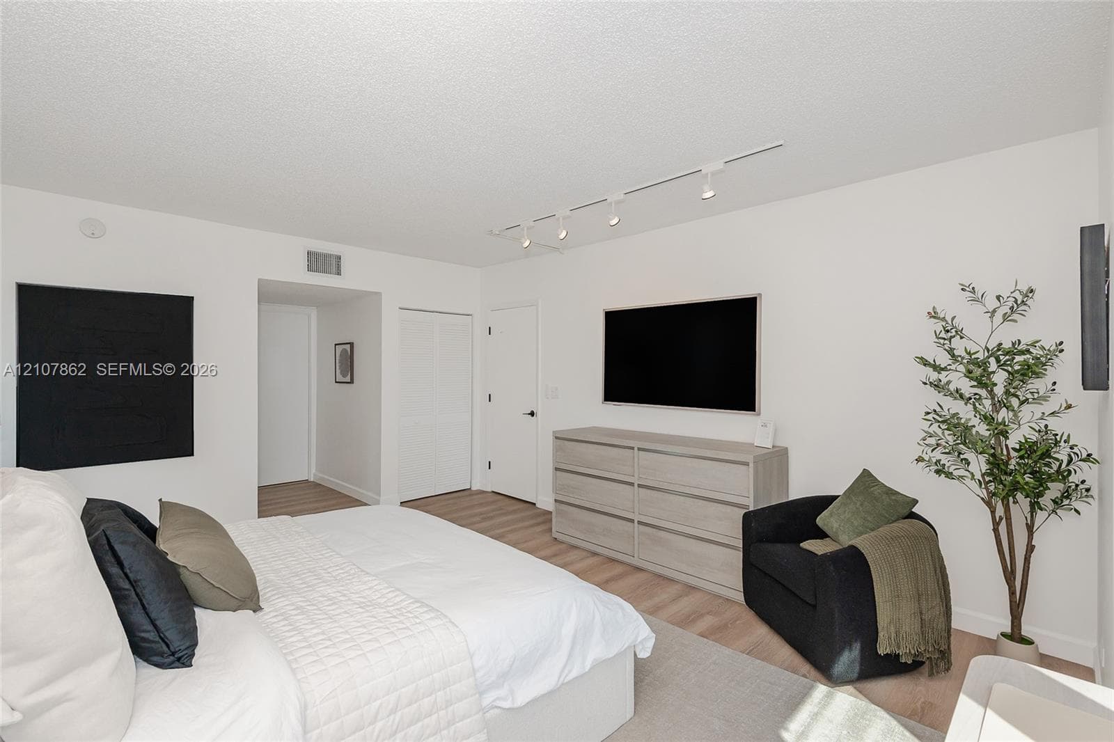 Wood-finish flooring, recessed track lighting, and crisp white walls