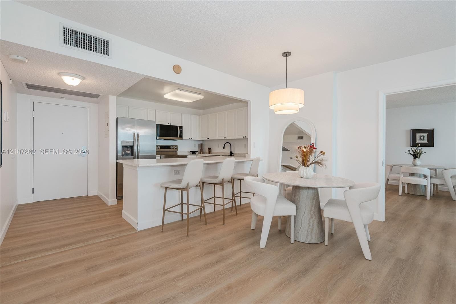 Kitchen featuring white cabinetry, wood-finish flooring, a breakfast bar, and stainless steel appliances