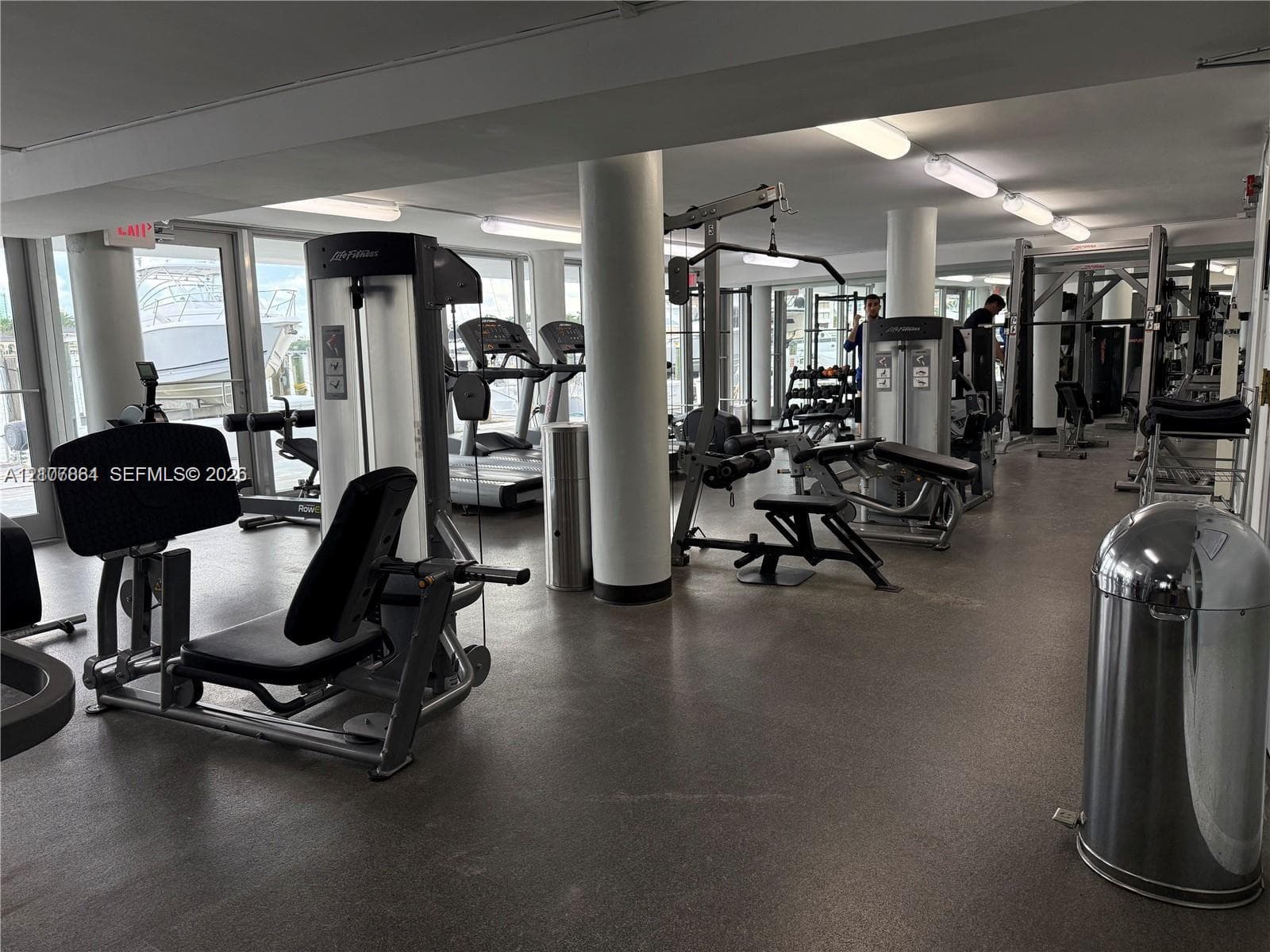 Fitness center featuring rubber flooring, floor-to-ceiling glass doors, and structural support columns
