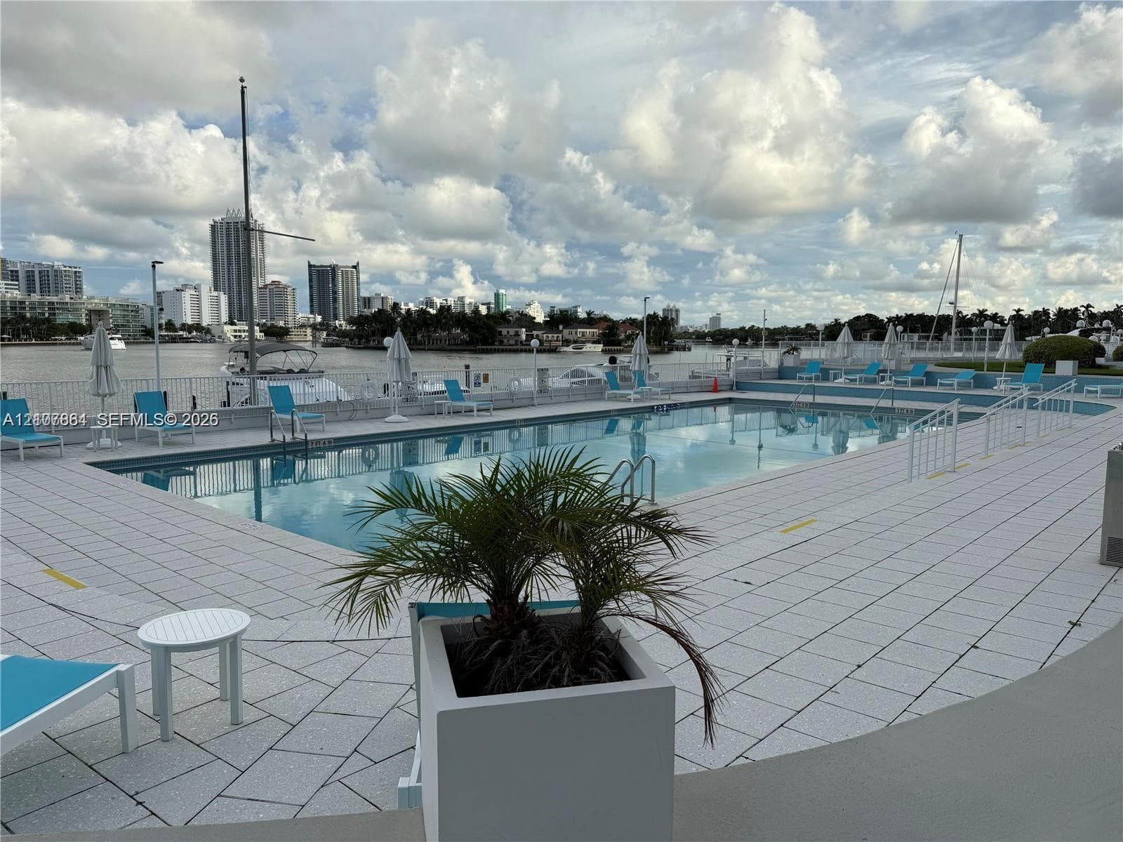 Inground swimming pool with a tile surround and metal perimeter fencing, situated along the waterfront