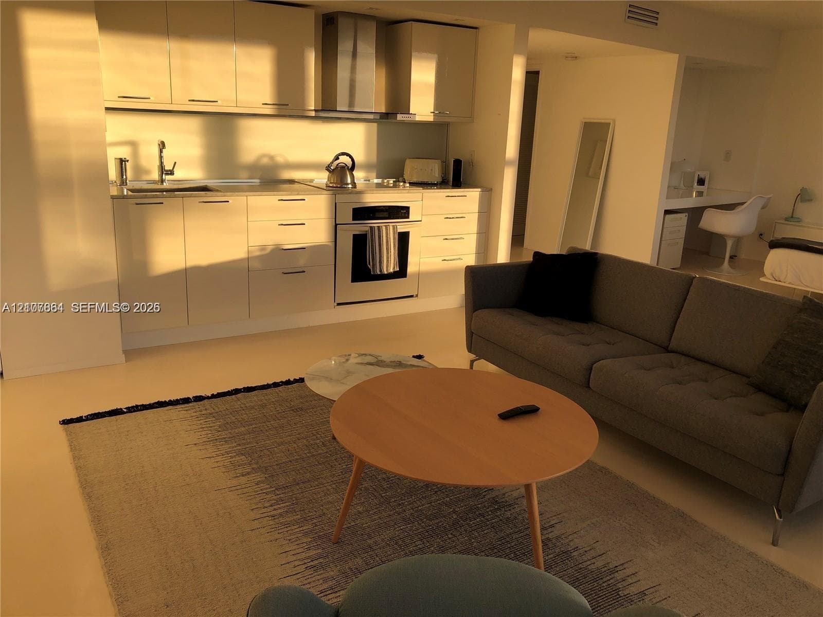 Glossy flat-panel cabinetry, stainless steel range with overhead vent hood, and solid-surface countertops
