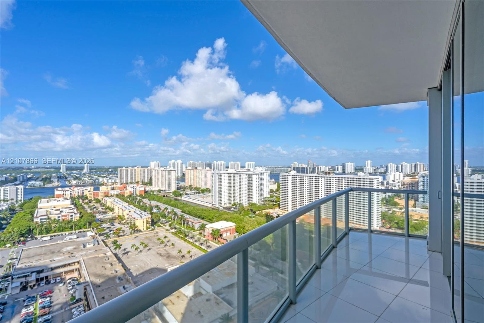 Covered balcony featuring glass paneled railings and large-format tile flooring