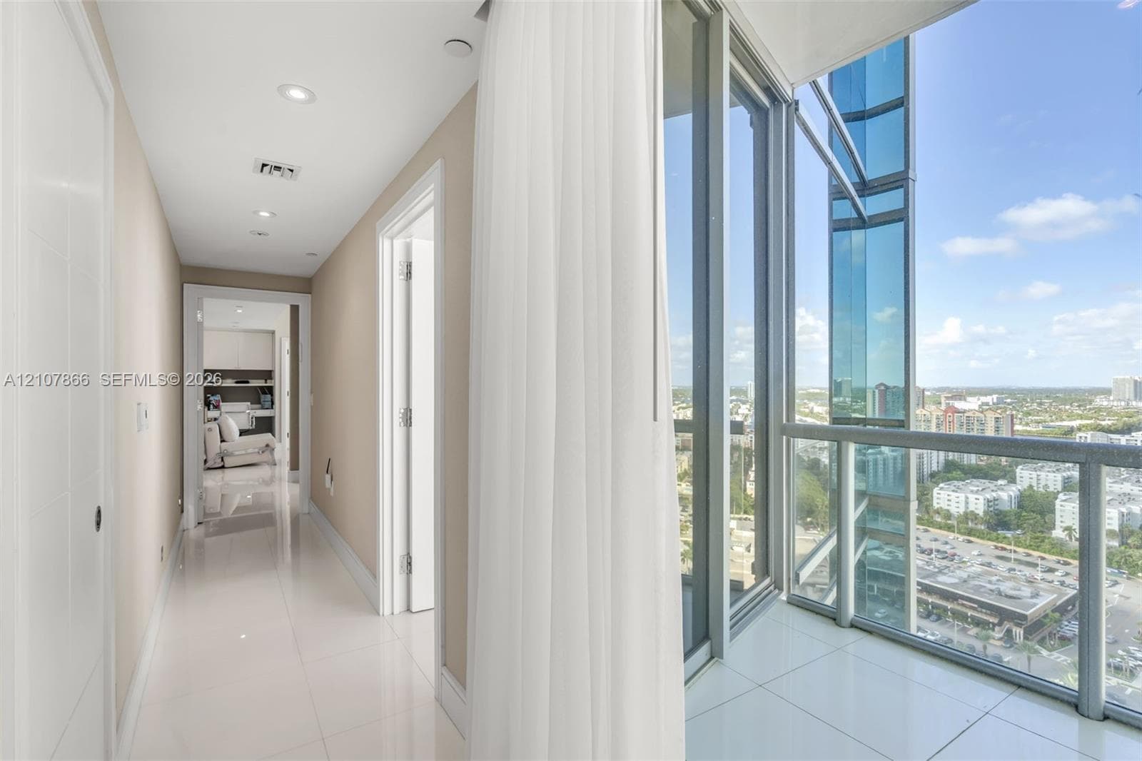 Hallway featuring large-format tile flooring, recessed lighting, and floor-to-ceiling glass paneling with metal framing