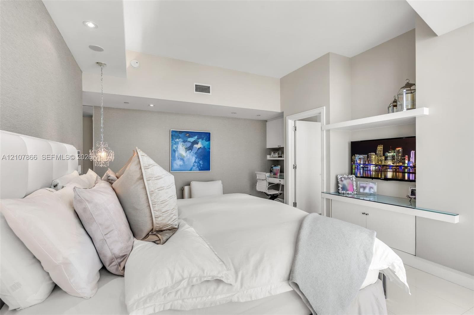 Built-in media console with glass shelving, integrated desk area, recessed lighting, and decorative pendant fixture