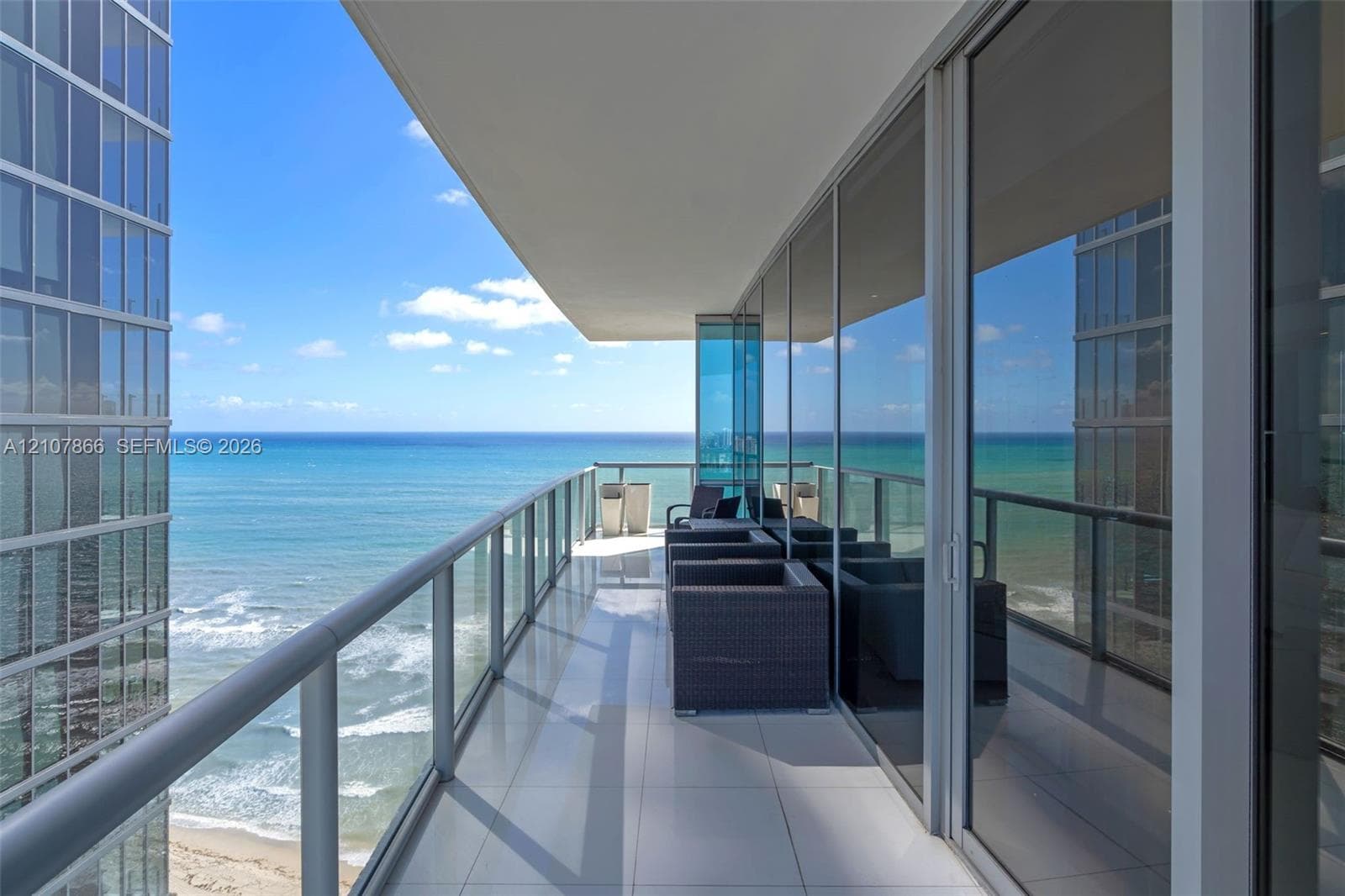 Covered balcony featuring floor-to-ceiling glass paneling, metal railing, and light-toned tile flooring