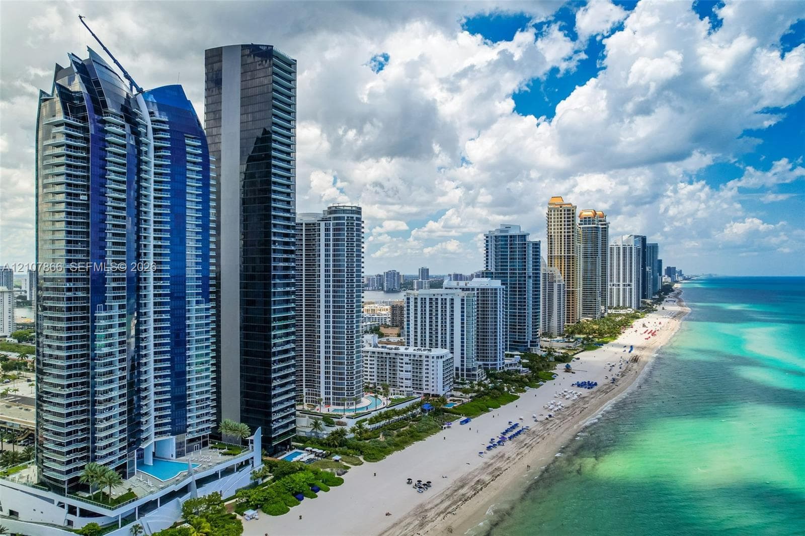 High-rise architecture featuring blue-tinted glass curtain walls and wrap-around balconies, situated directly on the Atlantic coastline with immediate beach access