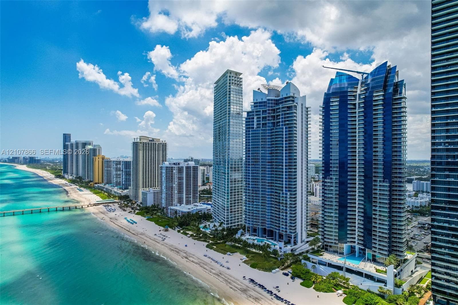Coastal high-rise buildings featuring floor-to-ceiling glass facades, prominent balconies, and direct oceanfront positioning