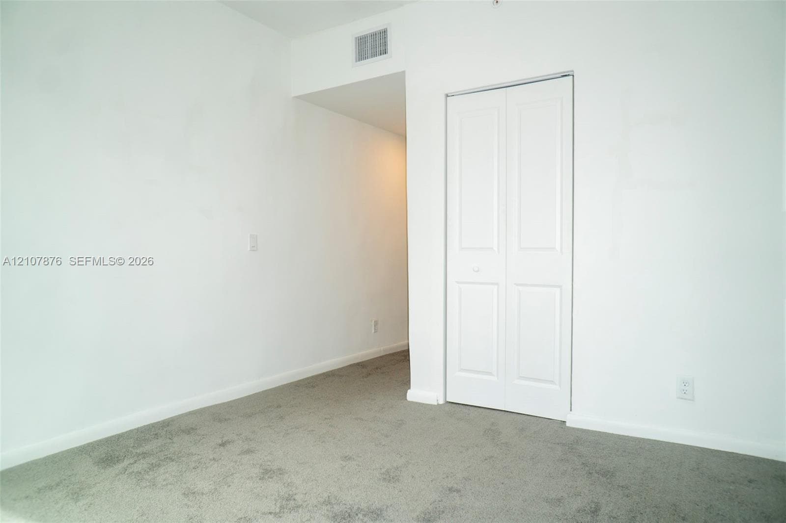 Neutral-toned carpeting and a closet with white paneled bi-fold doors