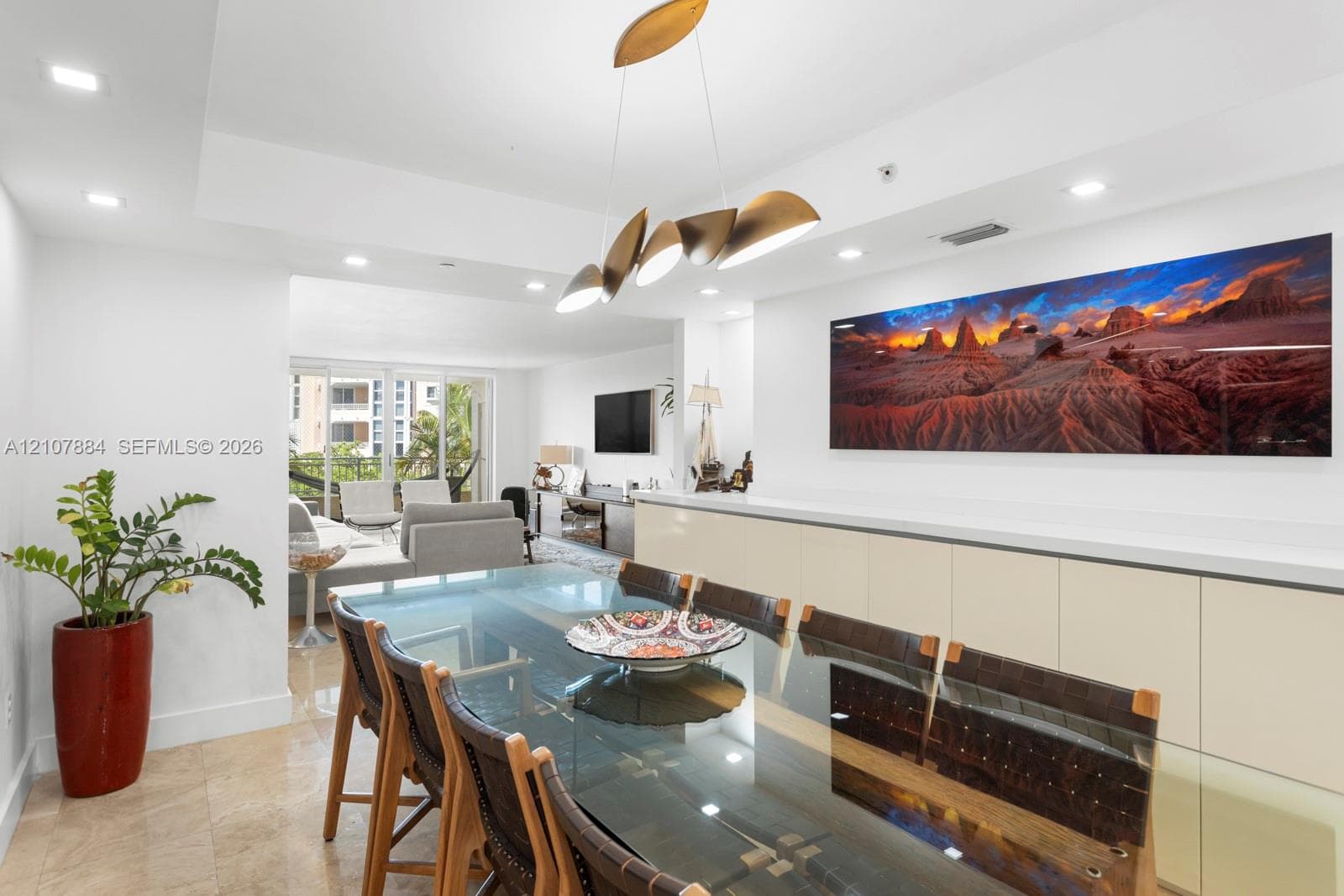Open concept interior featuring polished stone flooring, recessed lighting, integrated cabinetry with a stone countertop, and a contemporary multi-pendant brass light fixture