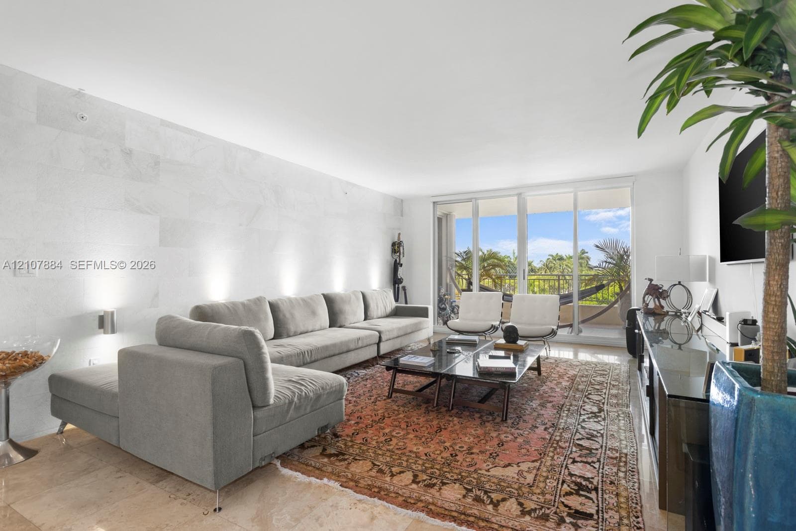 Living area featuring a floor-to-ceiling stone accent wall, polished stone flooring, and expansive sliding glass doors