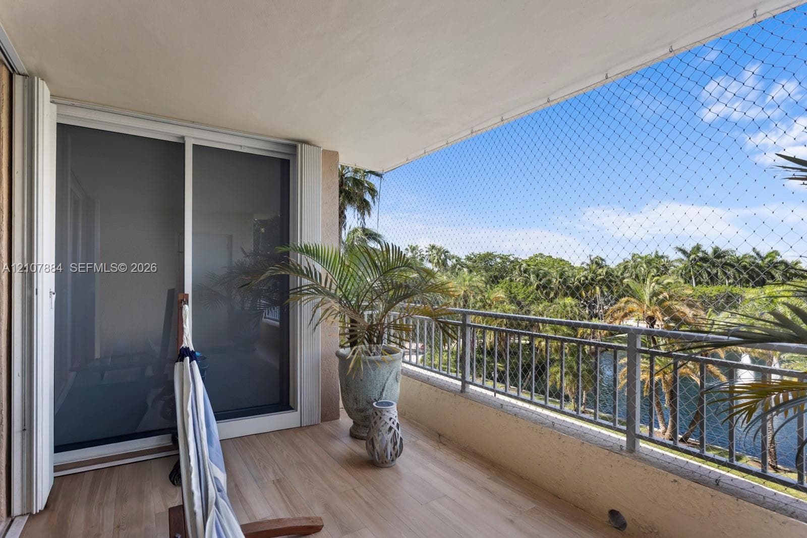 Covered balcony featuring wood-finish flooring, metal railing, and sliding glass entry door