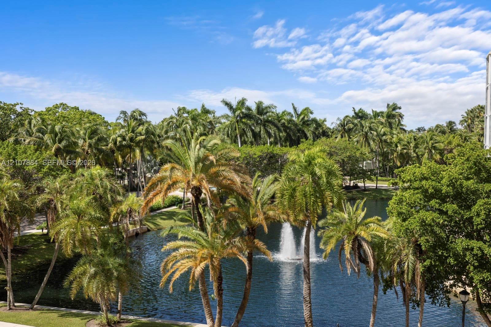 Water feature including a central fountain, surrounded by mature palm trees and established landscaping