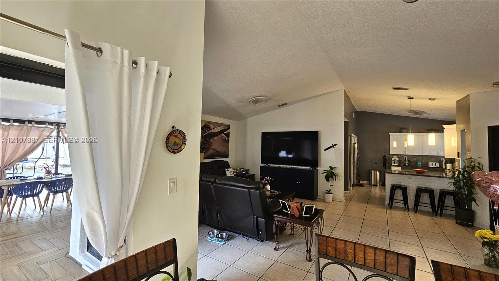 Open-concept interior featuring vaulted ceilings, tile flooring, and a kitchen island with pendant lighting