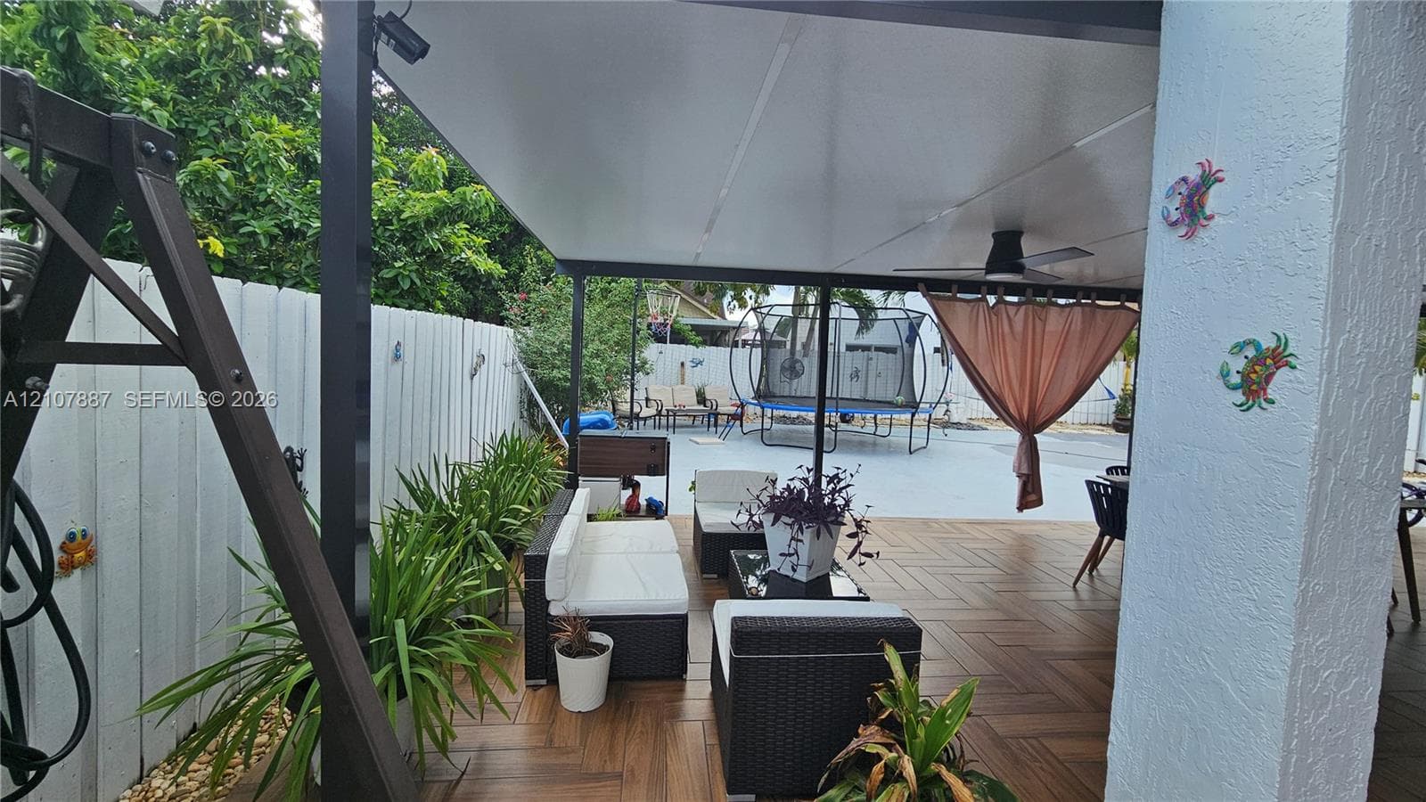 Covered outdoor patio featuring wood-finish tile flooring, a built-in ceiling fan, and privacy fencing