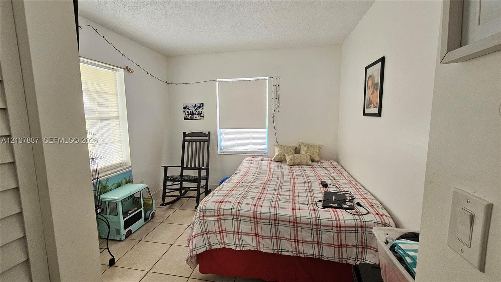 Neutral-toned room featuring tiled flooring and two windows with roller shades