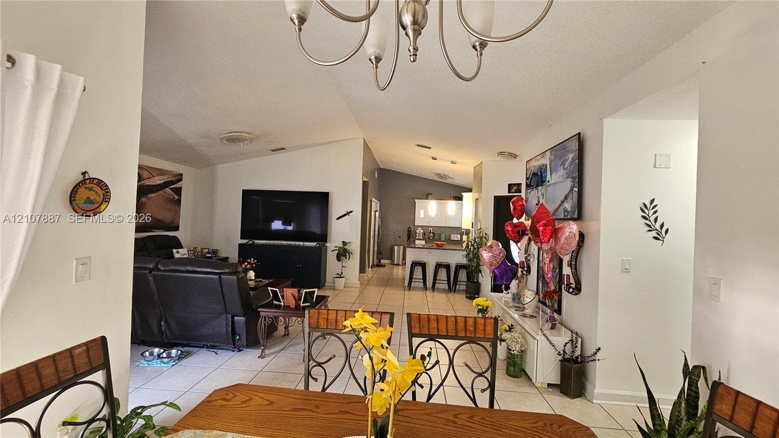 Vaulted ceilings, tile flooring, and a multi-arm chandelier featuring brushed metal finish