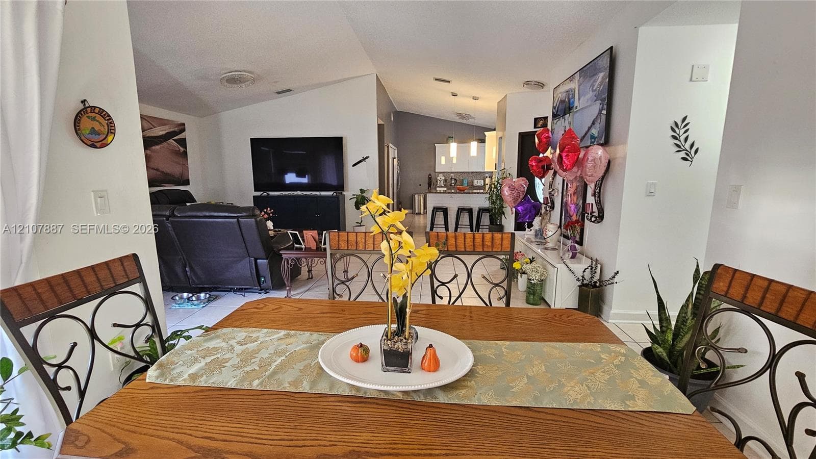 Vaulted ceilings, tile flooring, and open-concept design featuring a central kitchen island with bar-style seating