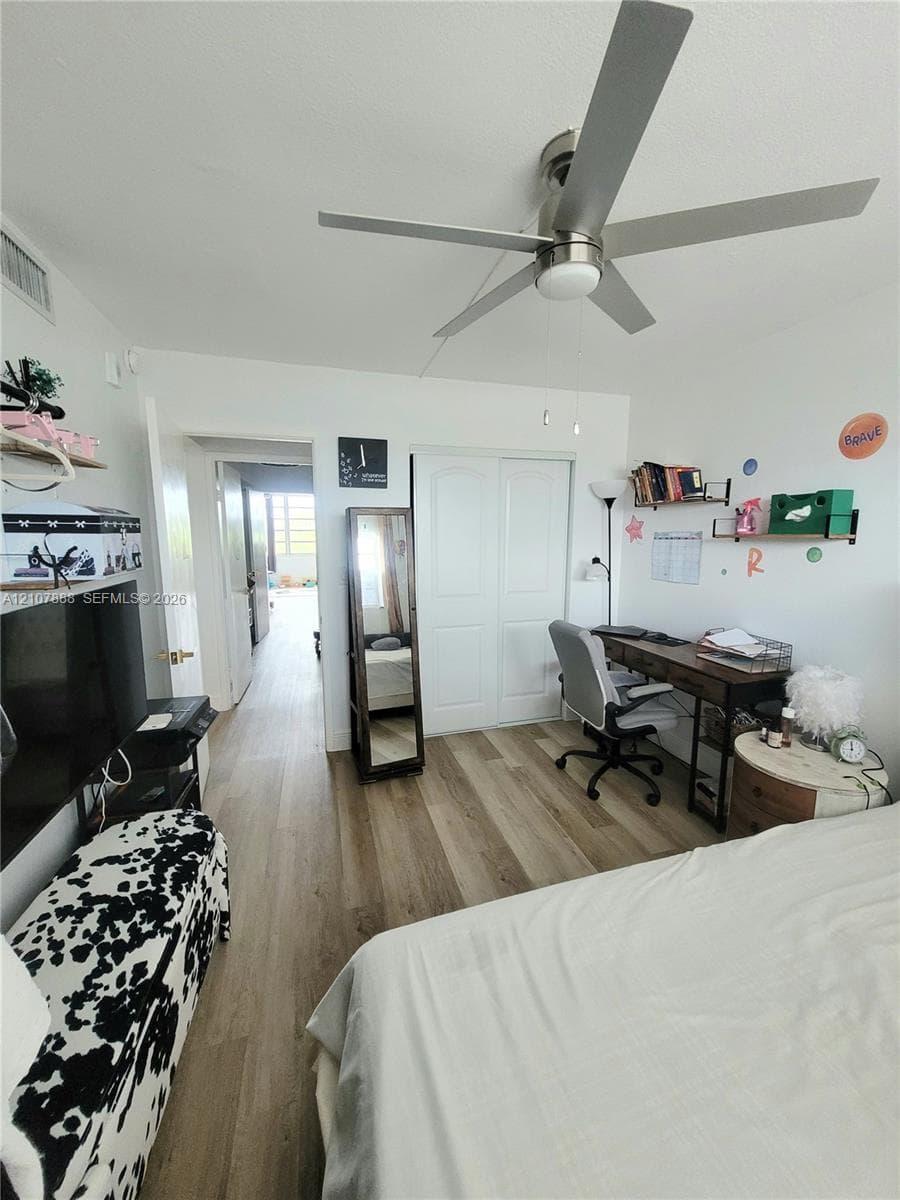 Wood-finish flooring, brushed nickel ceiling fan with integrated lighting, and closet with double doors