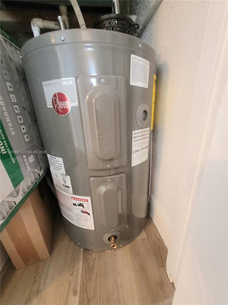 Vertical electric water heater featuring a cylindrical steel tank and brass pressure release valve