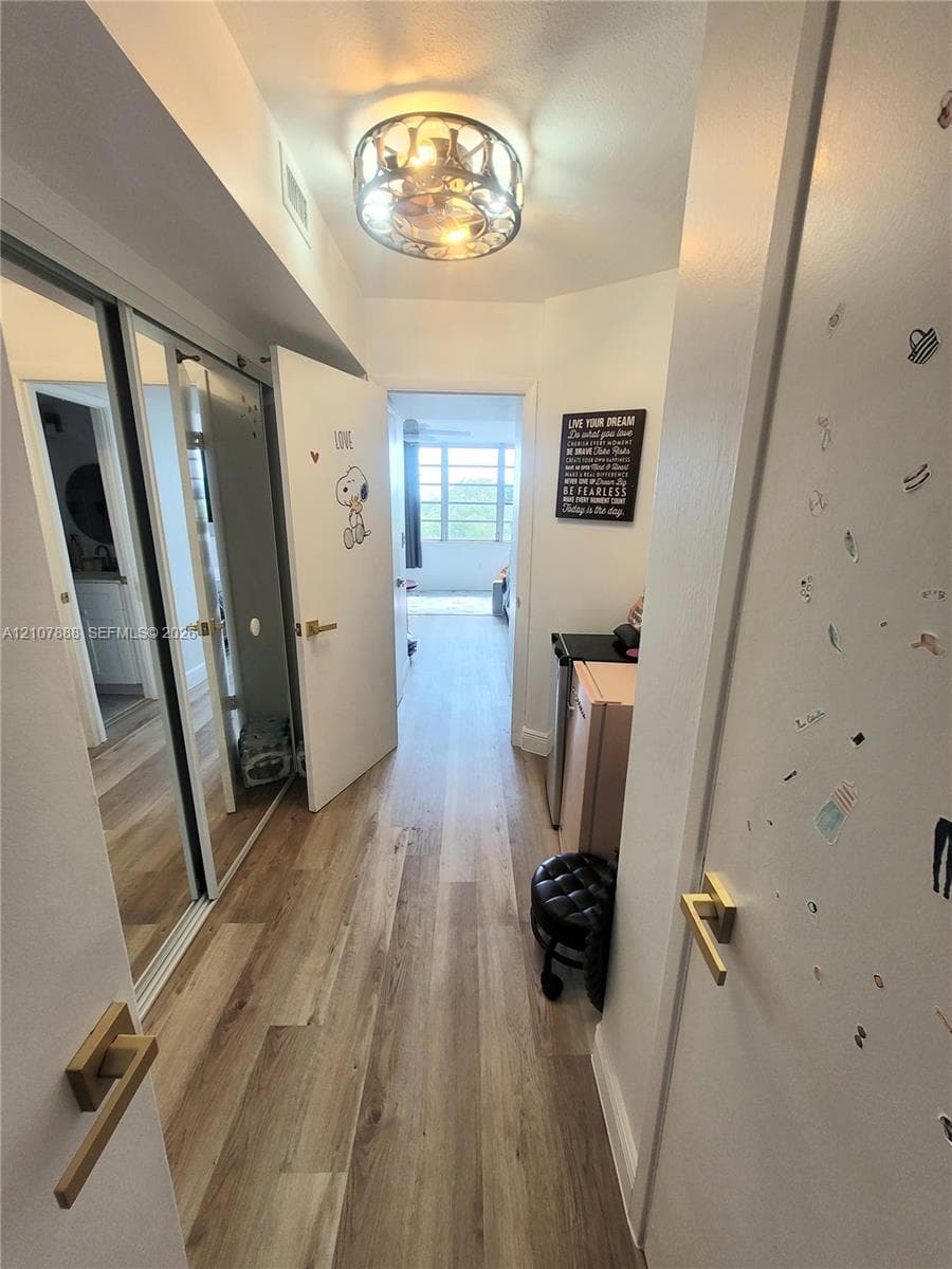 Wood-finish flooring, mirrored sliding closet doors, and decorative flush-mount ceiling lighting