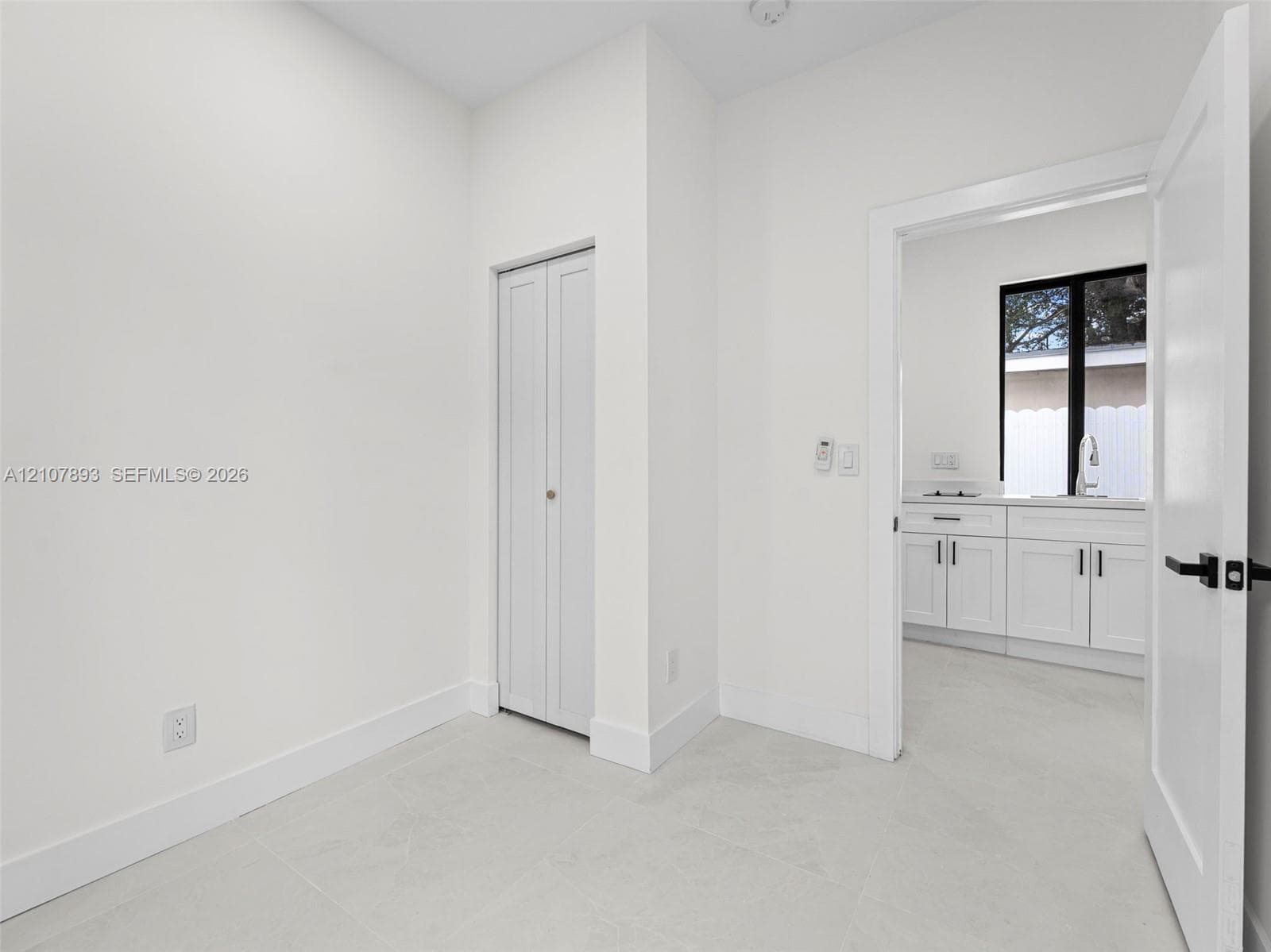 Neutral-toned tile flooring, bi-fold closet doors, and interior doors featuring matte black hardware