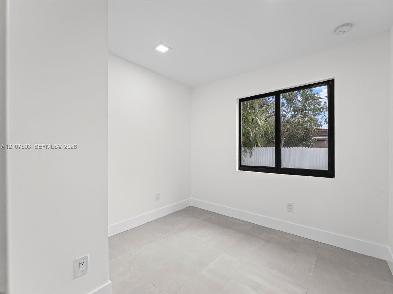 Neutral-toned tile flooring, recessed ceiling lighting, and a window with a black frame