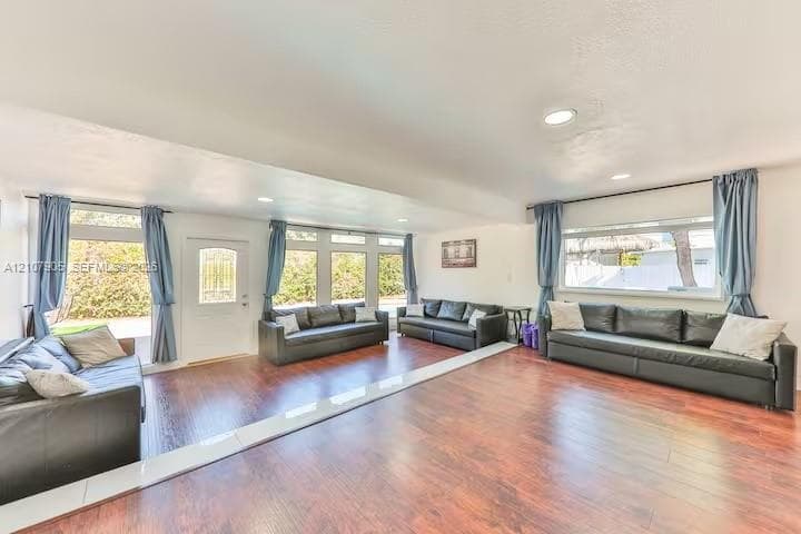 Open-concept interior featuring wood-finish flooring, extensive windows, recessed lighting, and a white paneled entry door