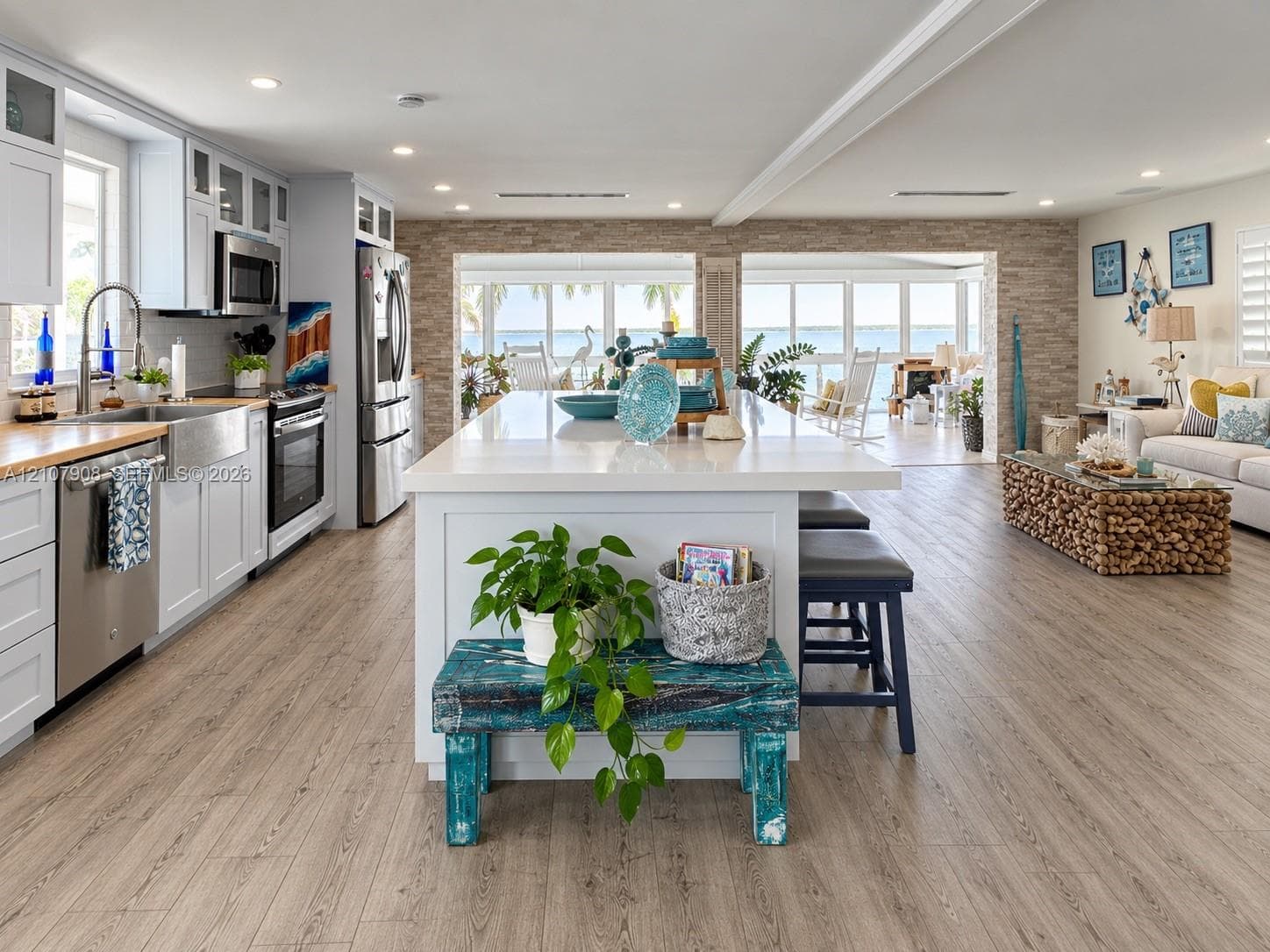 Kitchen featuring white shaker-style cabinetry, stainless steel appliances, a farmhouse sink, a central island with a solid surface countertop, and wood-finish flooring