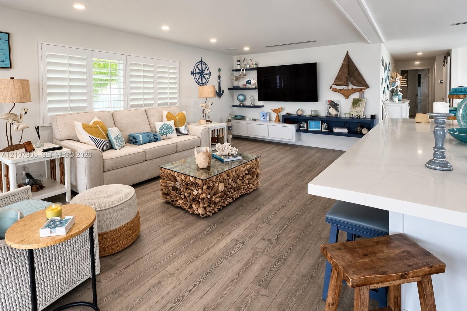 Open-concept space featuring wood-finish flooring, recessed lighting, plantation shutters, custom built-in cabinetry, and a stone-topped island