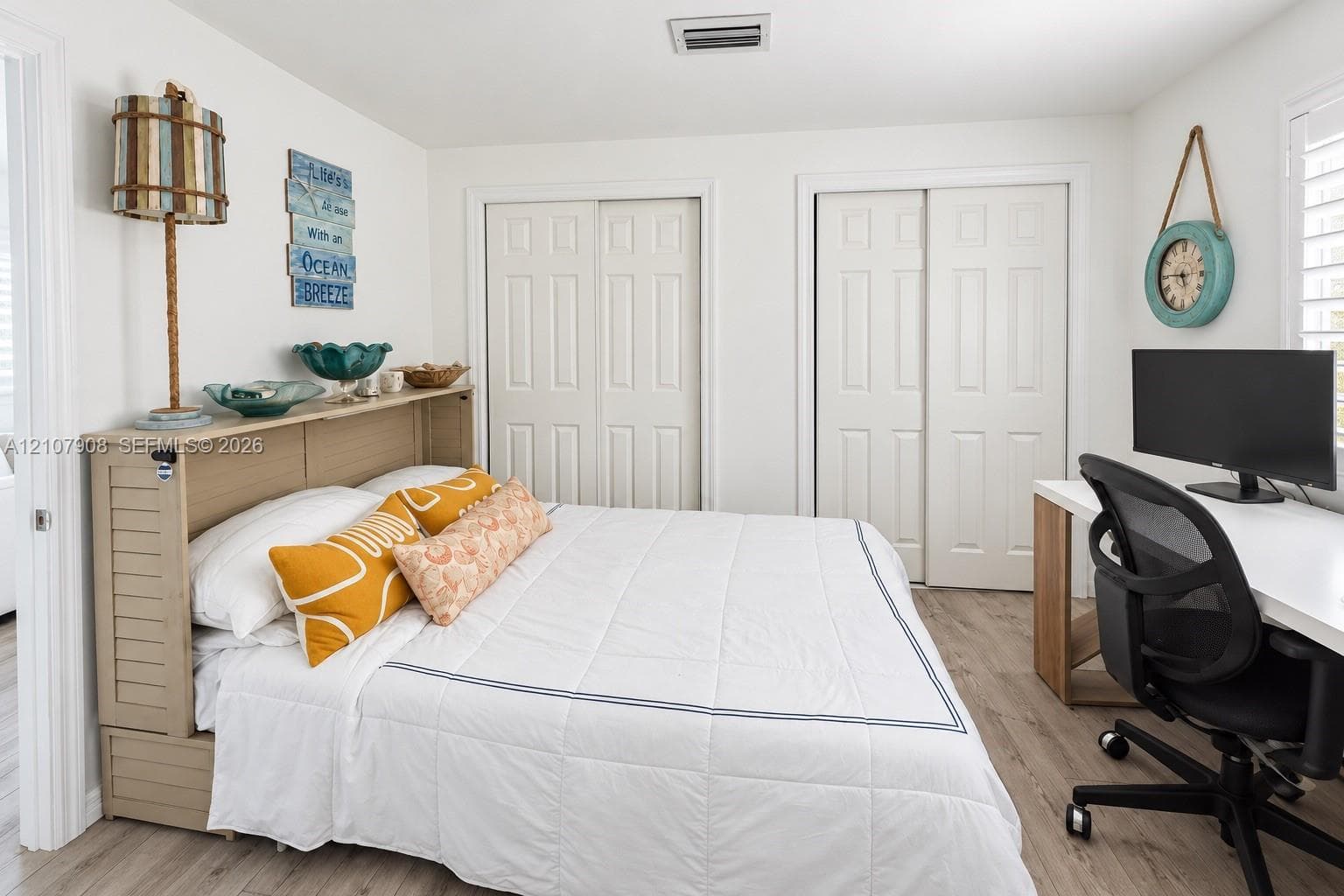 Room featuring wood-finish flooring, two sets of white paneled bifold closet doors, and plantation shutters