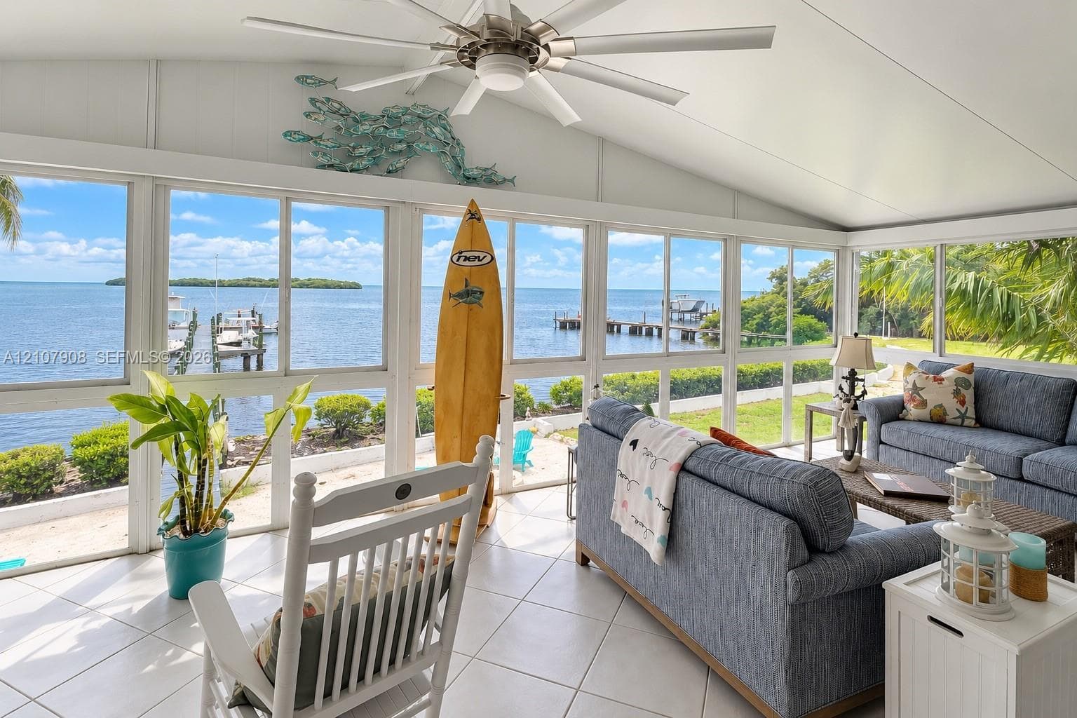 Enclosed patio featuring floor-to-ceiling screen panels, vaulted ceiling with integrated paddle fan, and ceramic tile flooring