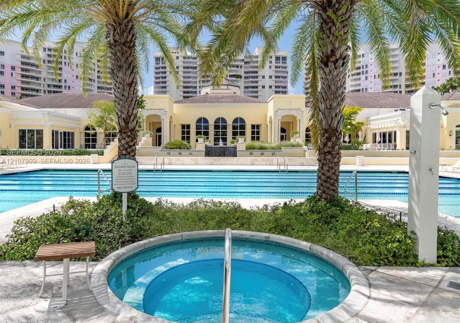 Outdoor swimming pool with multiple lanes, stone-tiled spa, and mature palm trees