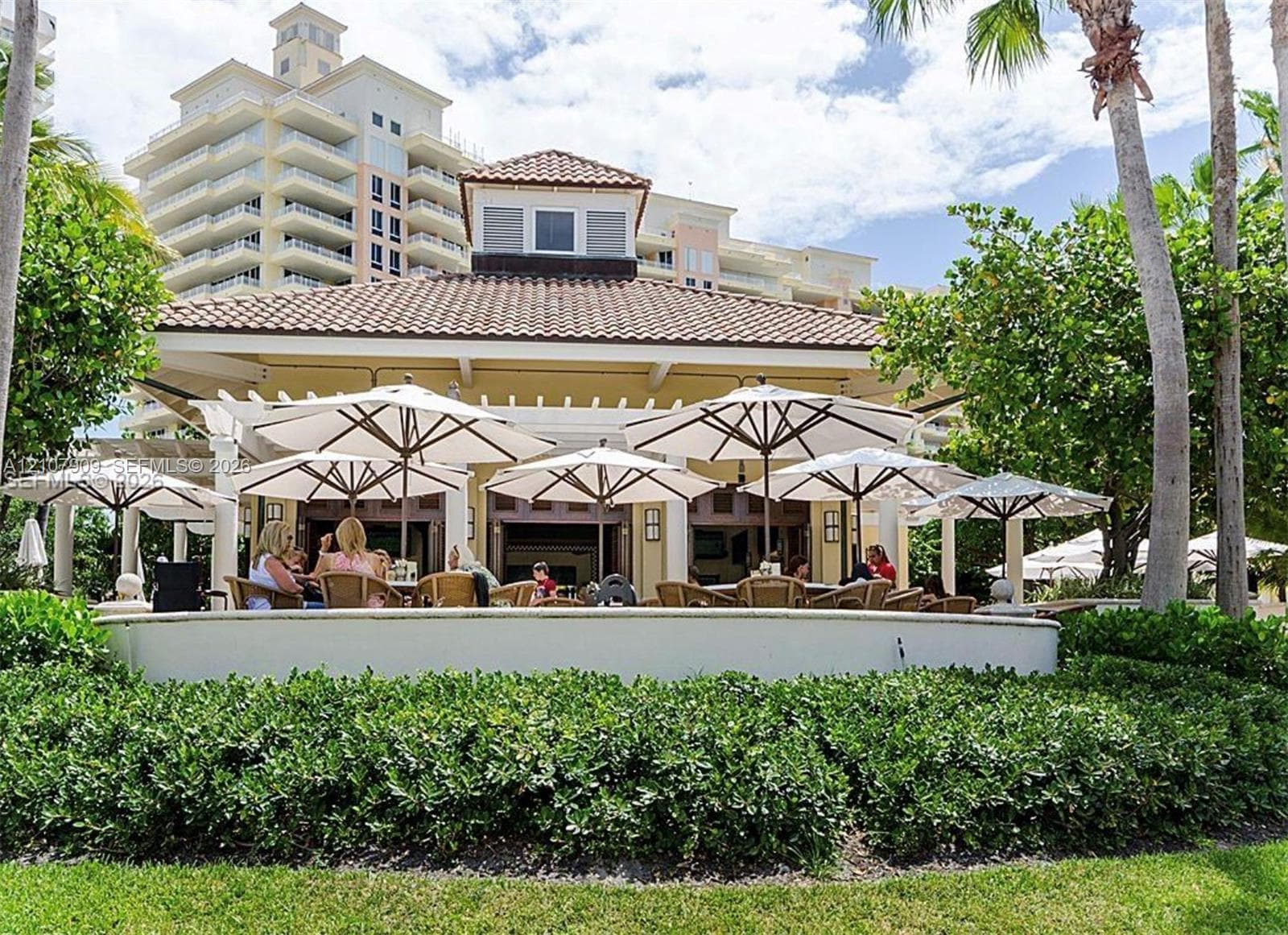 Outdoor pavilion featuring a tile roof, structural pergola, masonry perimeter wall, and mature landscaping