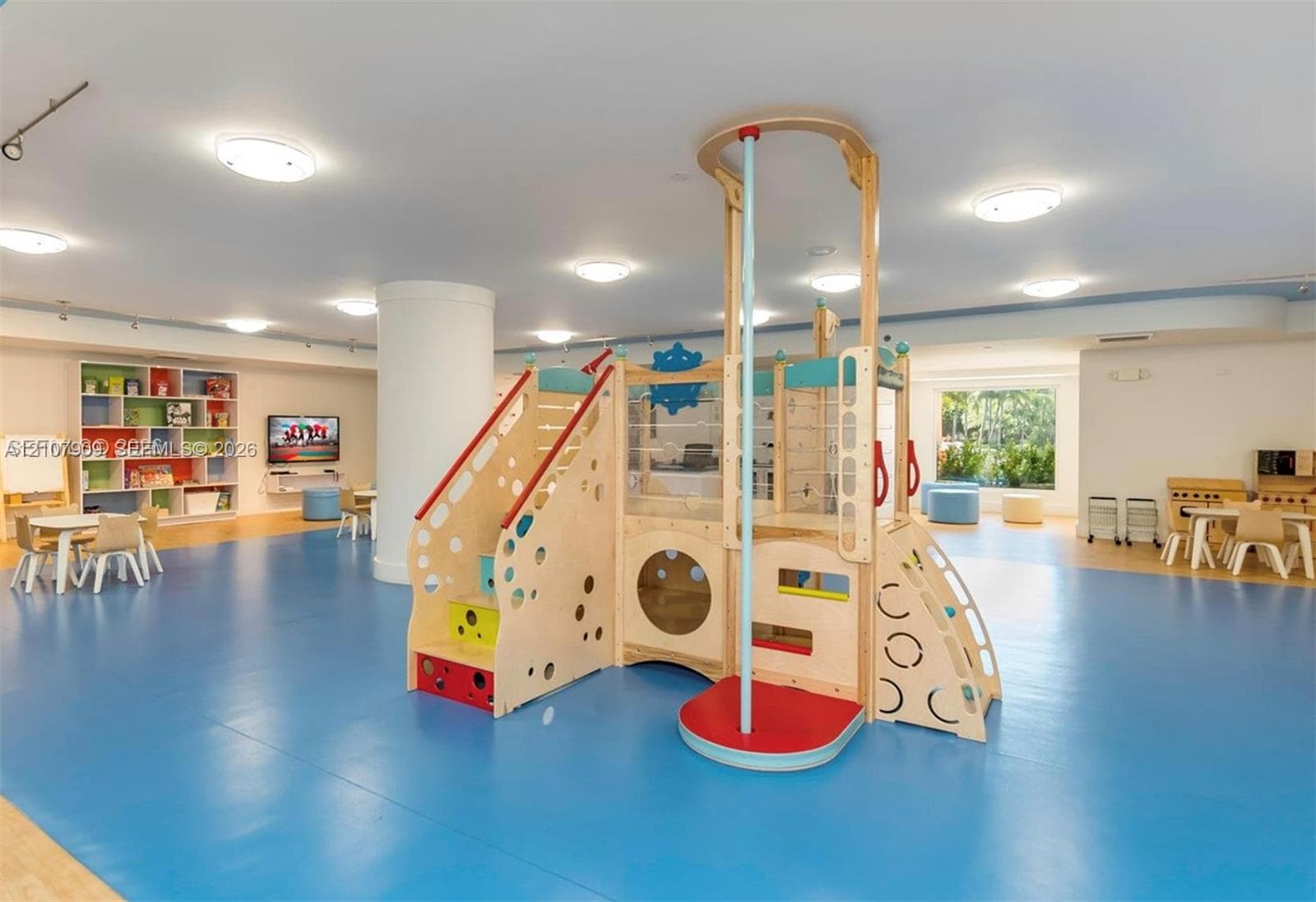 Open-concept recreation area featuring smooth flooring, recessed ceiling lighting, a structural column, and built-in wall shelving