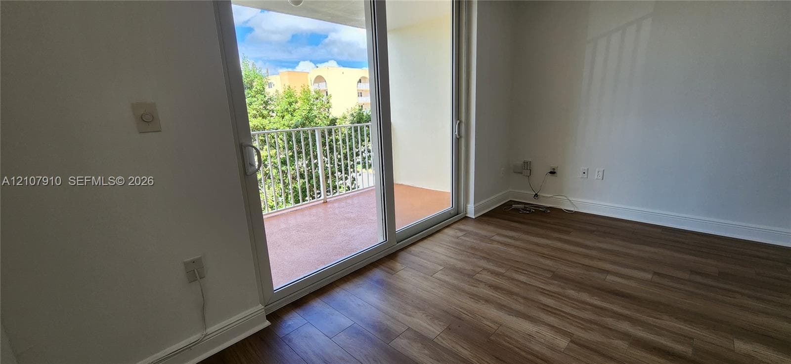Living space featuring wood-finish flooring, sliding glass doors, and an attached balcony with a metal railing