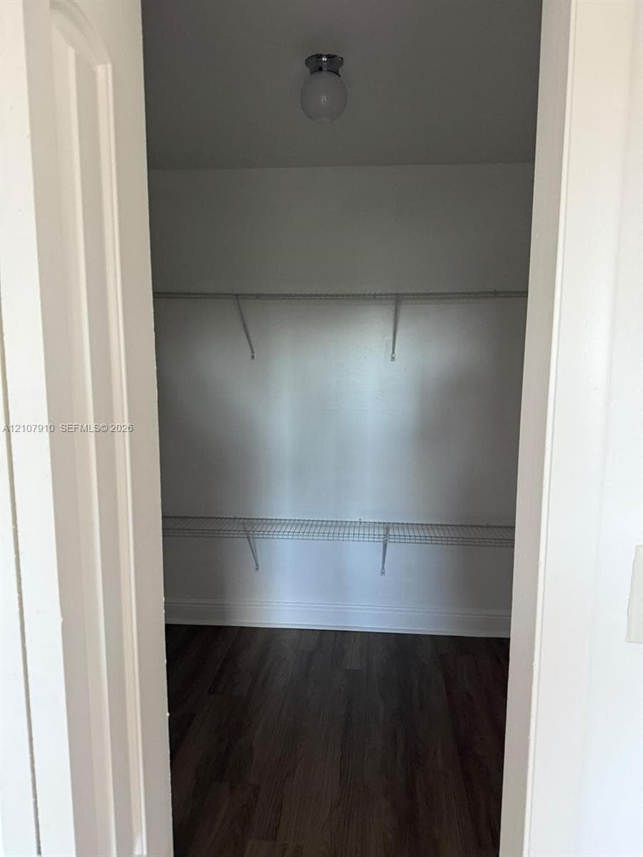 Storage space featuring wood-finish flooring, two-tier white wire shelving, and a dome-style flush mount ceiling light