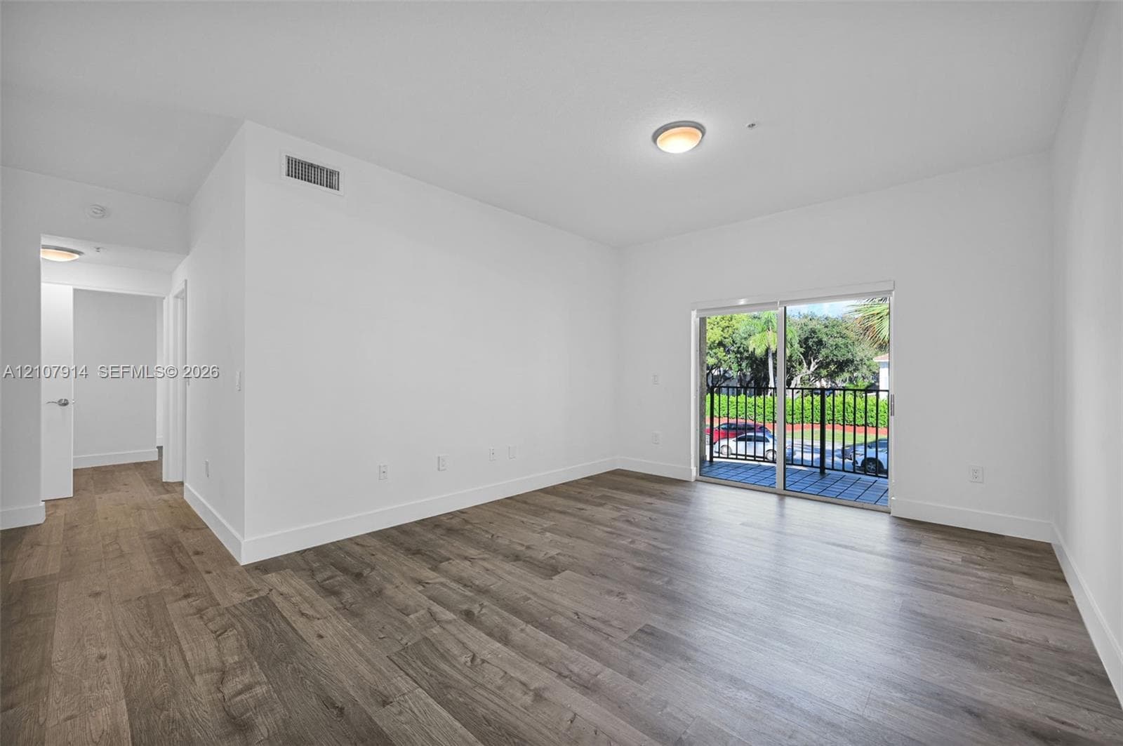 Open-concept room featuring wood-finish flooring, sliding glass doors, and a private balcony with metal railing