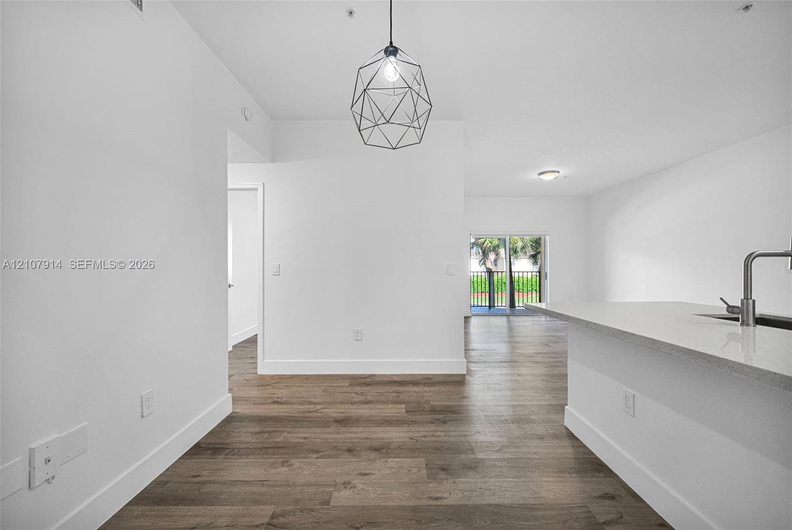 Wood-finish flooring throughout, geometric pendant lighting, stone-surface kitchen island, and metal-finish gooseneck faucet