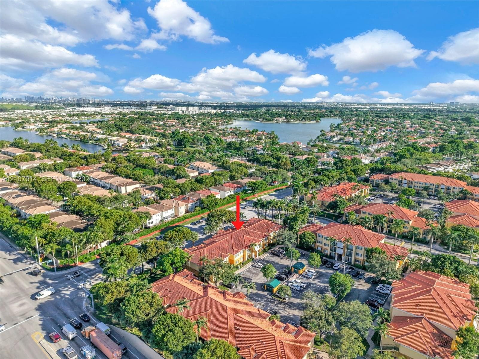 Aerial perspective featuring a multi-story residential building with a terracotta-style tiled roof, stucco exterior, and dedicated surface parking