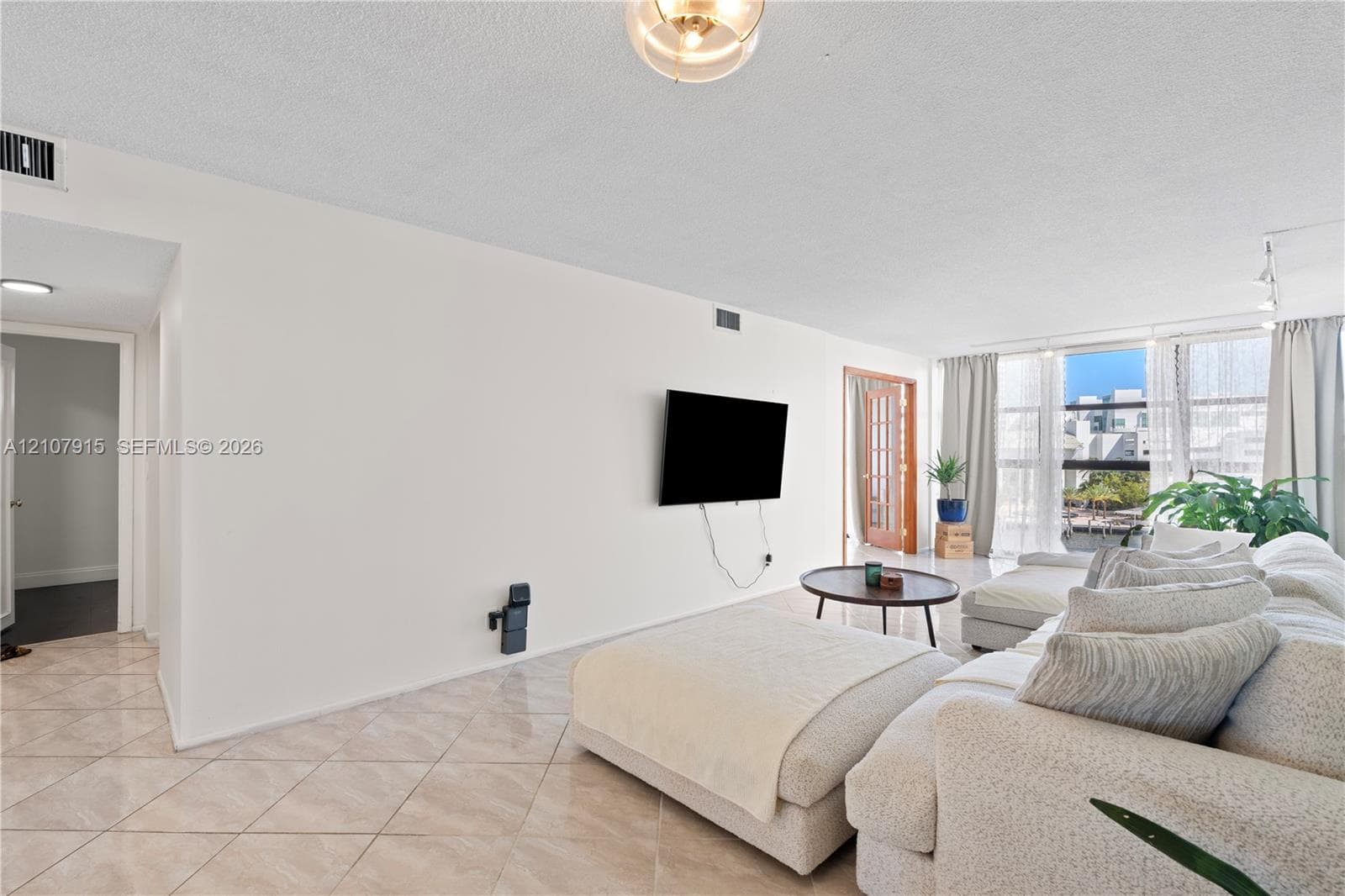 Open-concept room featuring light-colored tile flooring set on a diagonal, floor-to-ceiling windows, and wood-framed glass pane interior doors