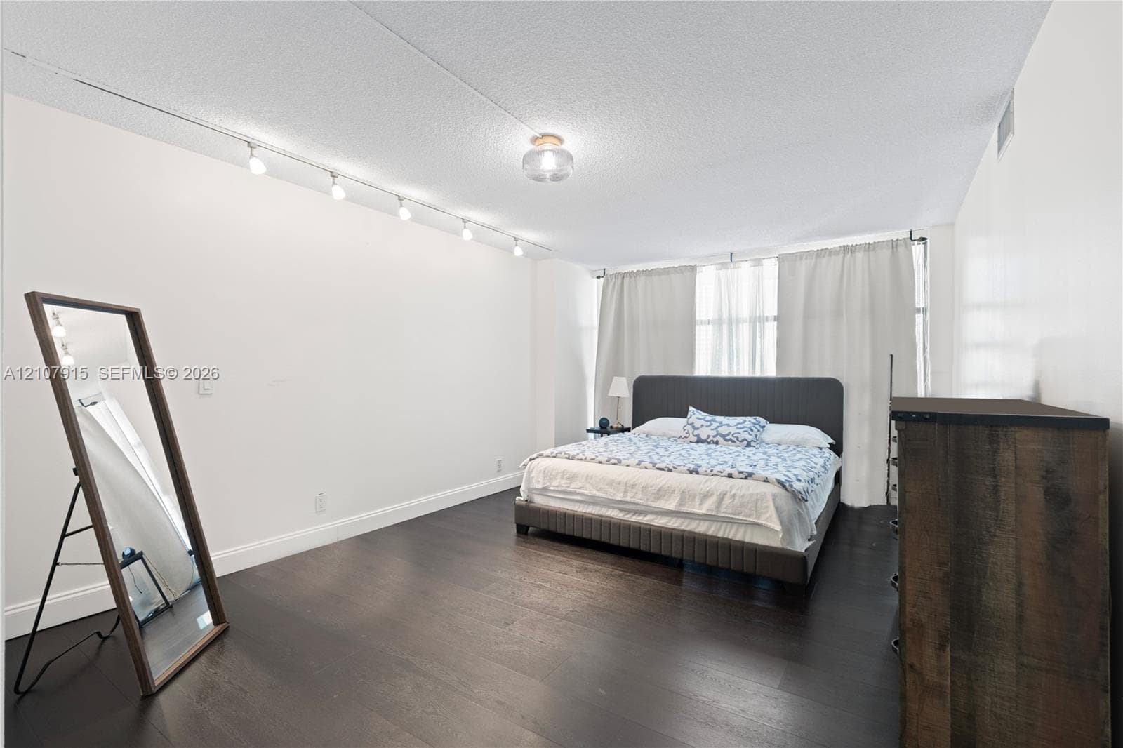 Interior space featuring dark wood-finish flooring, recessed ceiling lighting, track lighting, and expansive windows