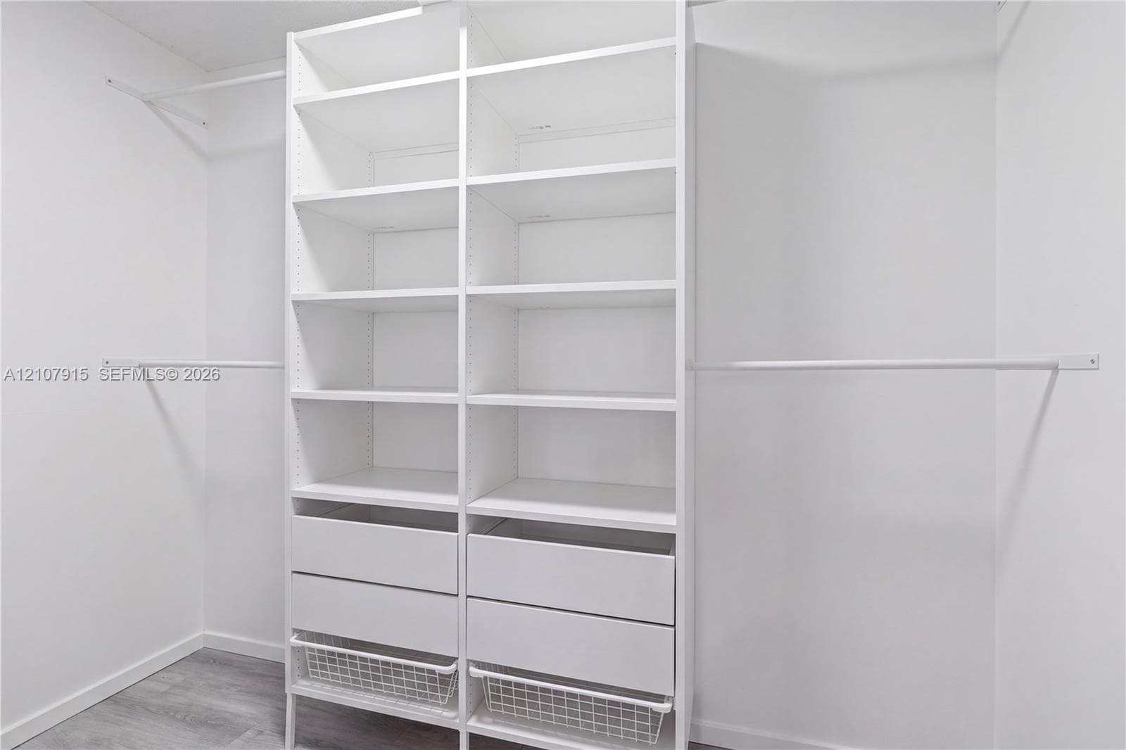 Custom white built-in shelving unit featuring adjustable storage racks, dual integrated drawers, wire sliding baskets, and dual metal hanging rods