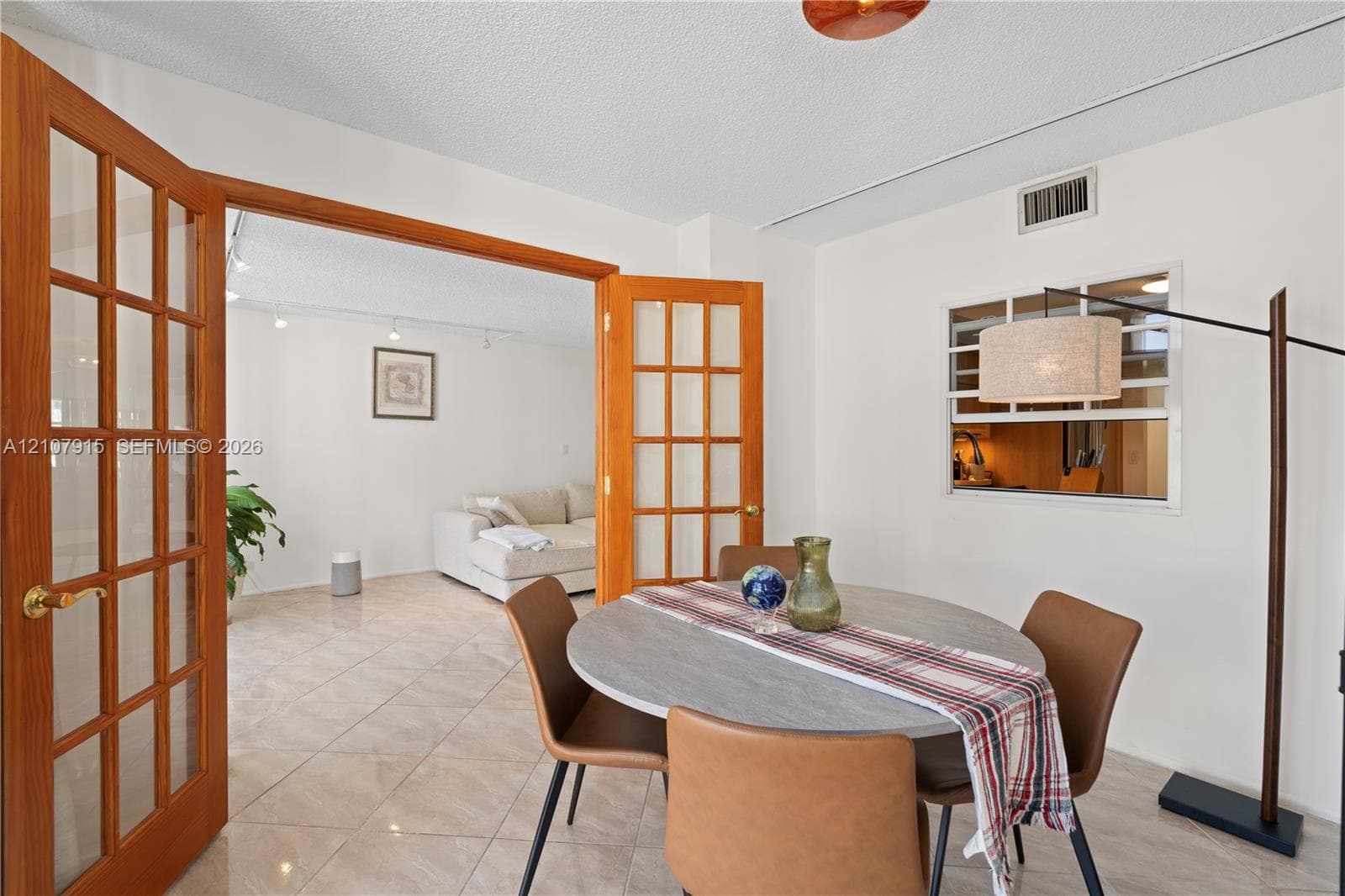 Interior space featuring wood-frame French doors, tile flooring, and a pass-through window with a fixed pane