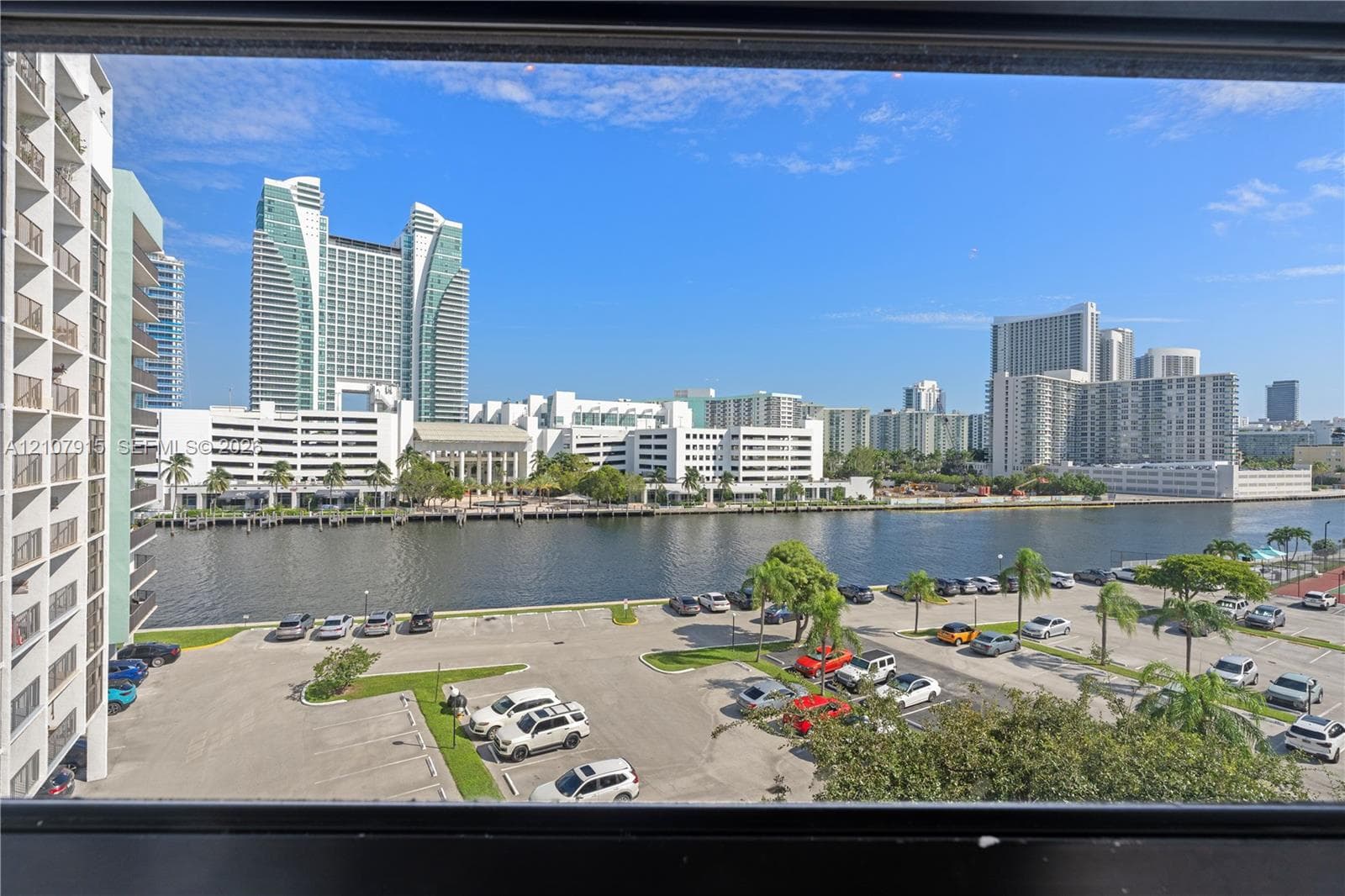 Waterfront perspective featuring high-rise urban architecture and paved parking area