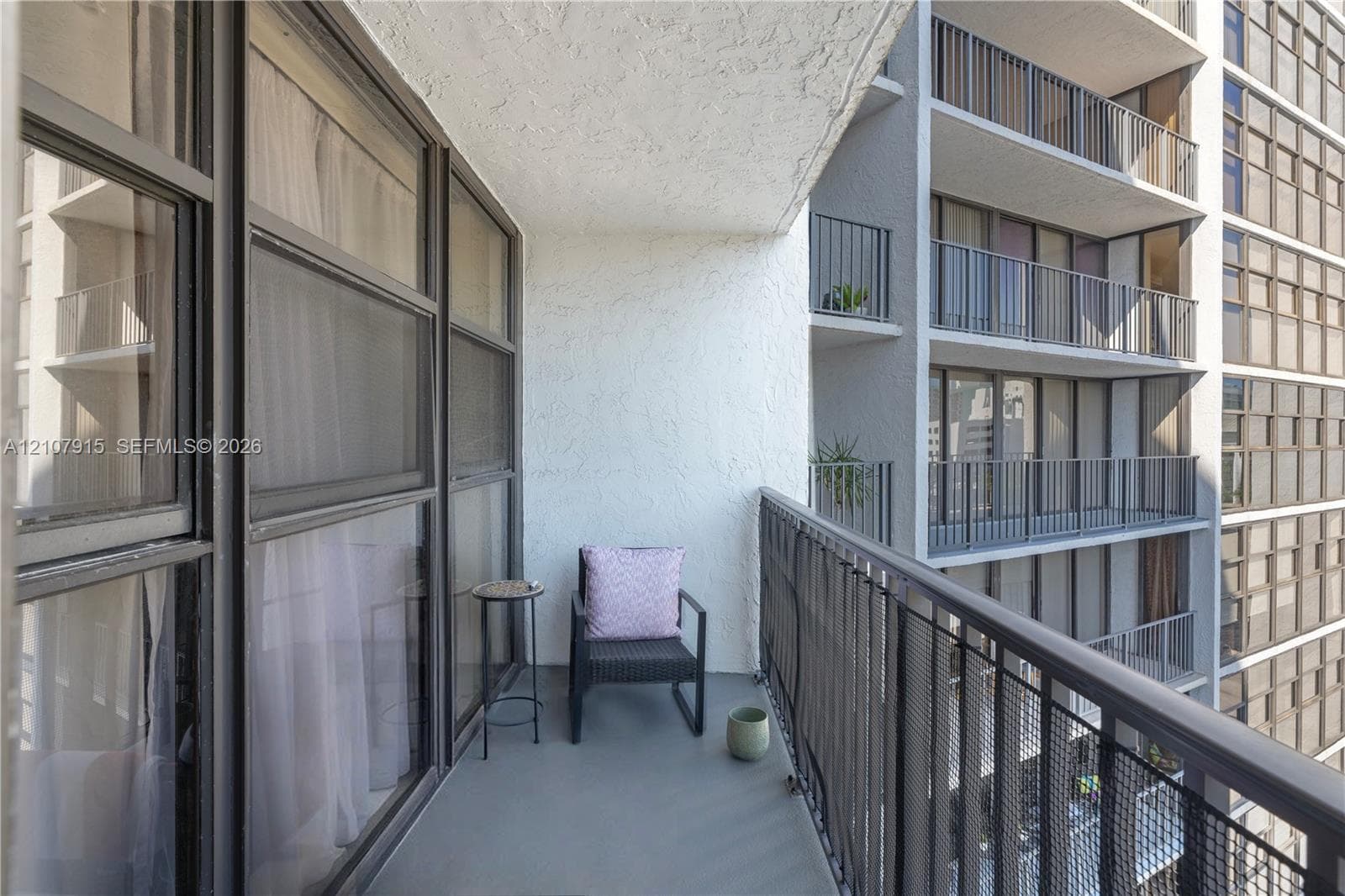 Private balcony featuring a concrete floor, textured stucco wall, and metal safety railing