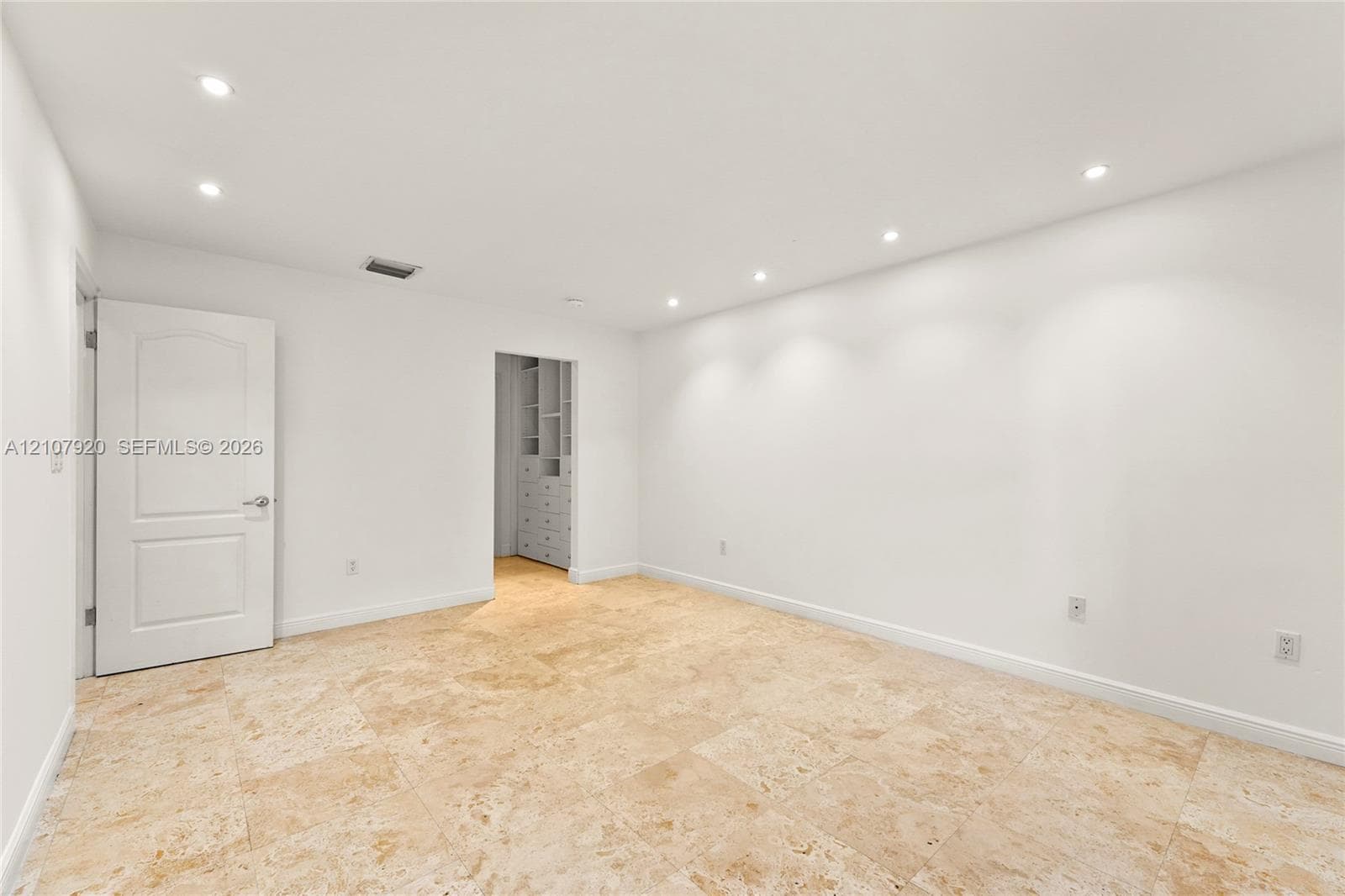Neutral-toned stone tile flooring, recessed ceiling lighting, and custom built-in cabinetry