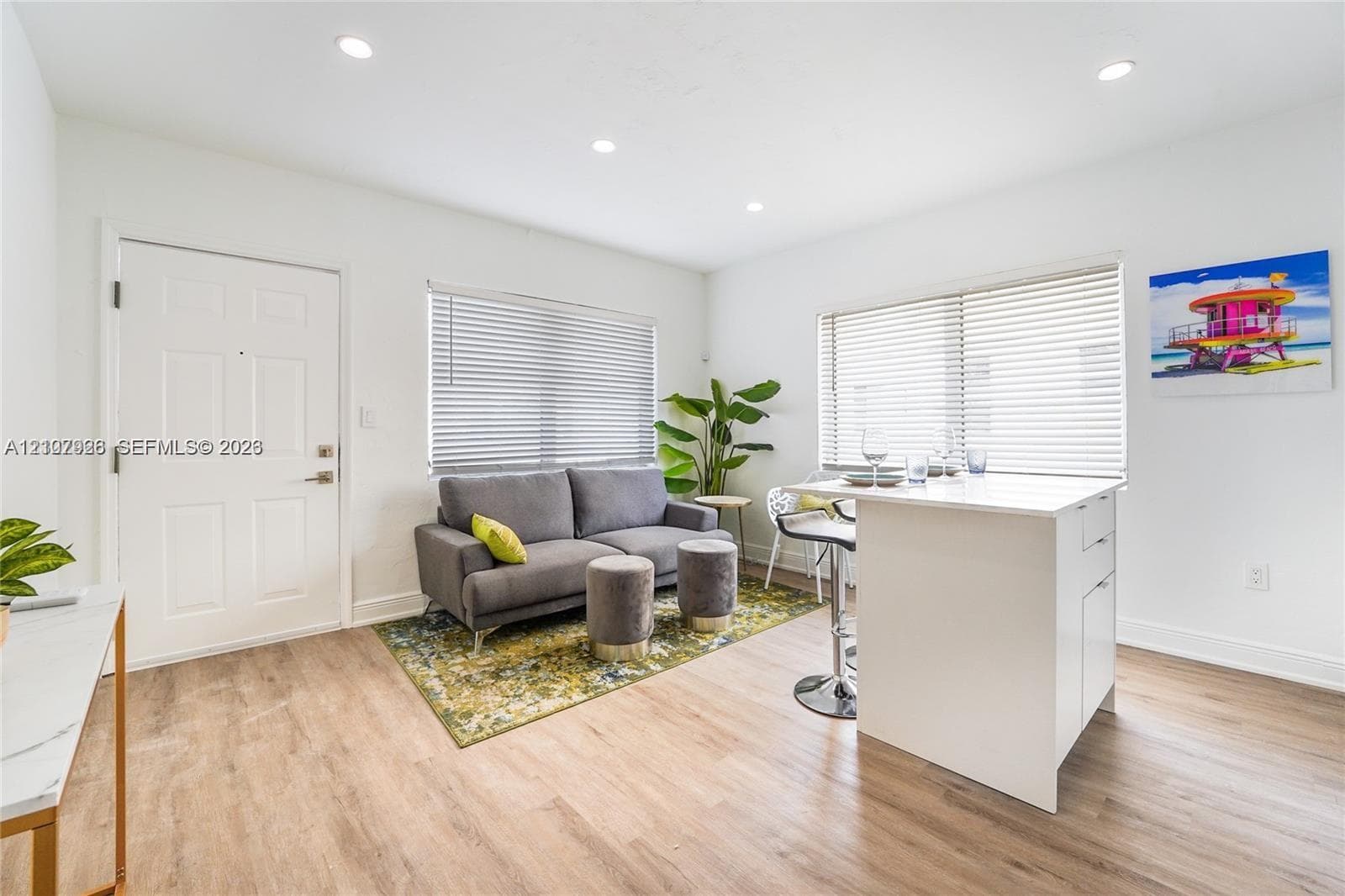 Interior featuring wood-finish flooring, recessed lighting, and a white kitchen island with solid surface countertop