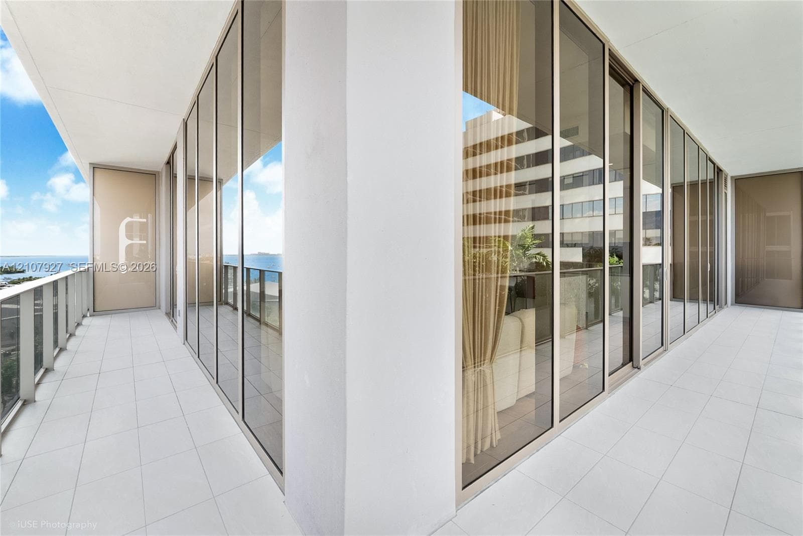Wrap-around terrace featuring large-format tile flooring, floor-to-ceiling glass paneling, and metal railing
