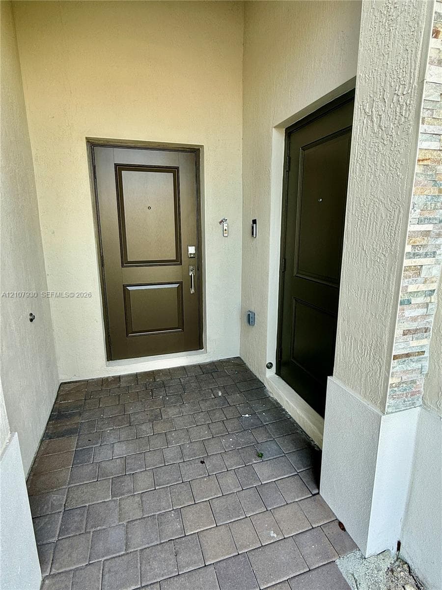 Covered entryway featuring paver flooring, dual paneled doors, and stacked stone exterior detailing